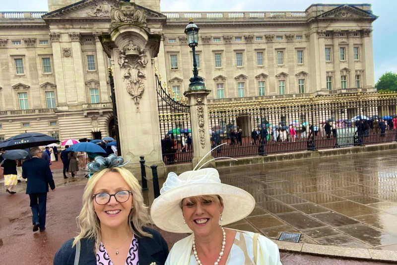 Charlotte Colesby in the fascinator with Janet McGookin in the hat at Buckingham Palace. Janet represented the Royal College of Speech and Language Therapists (RCSLT)