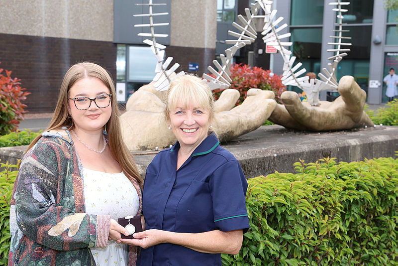 Janine handing over the fob watch to Tegan in front of the ‘healing hands’ statue in front of the Emergency Department at New Cross Hospital